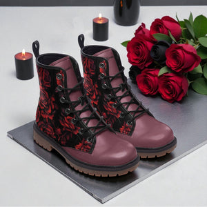 A pair of red floral boots sits on a gray surface, accompanied by a bouquet of red roses and two lit candles.