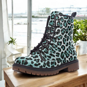 A leopard print boot is displayed on a wooden surface, with a window and plants visible in the background.