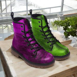 A pair of colorful, patterned boots in purple and green are displayed on a wooden surface, with a window and greenery visible in the background.