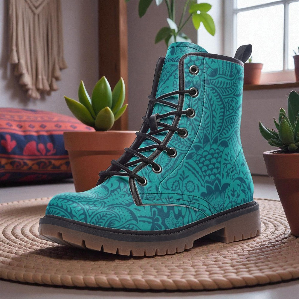 A teal patterned boot is displayed on a woven mat, surrounded by potted plants and a colorful cushion in a cozy, homely setting.