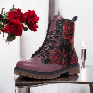 A pair of purple boots with a floral print design, placed on a table next to a bouquet of red roses.