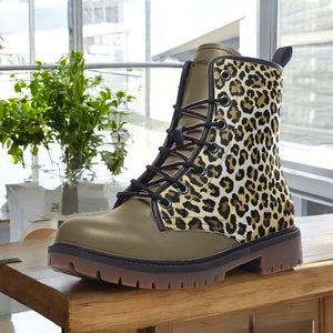 A leopard print boot is displayed on a wooden surface, with a window and potted plants in the background.