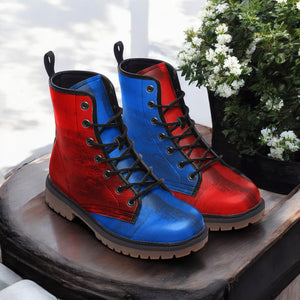 A pair of red and blue boots with black laces, placed on a wooden surface next to a potted plant with white flowers.