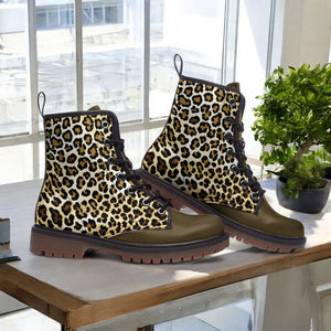 A pair of leopard print boots sits on a wooden surface, with a potted plant visible in the background.