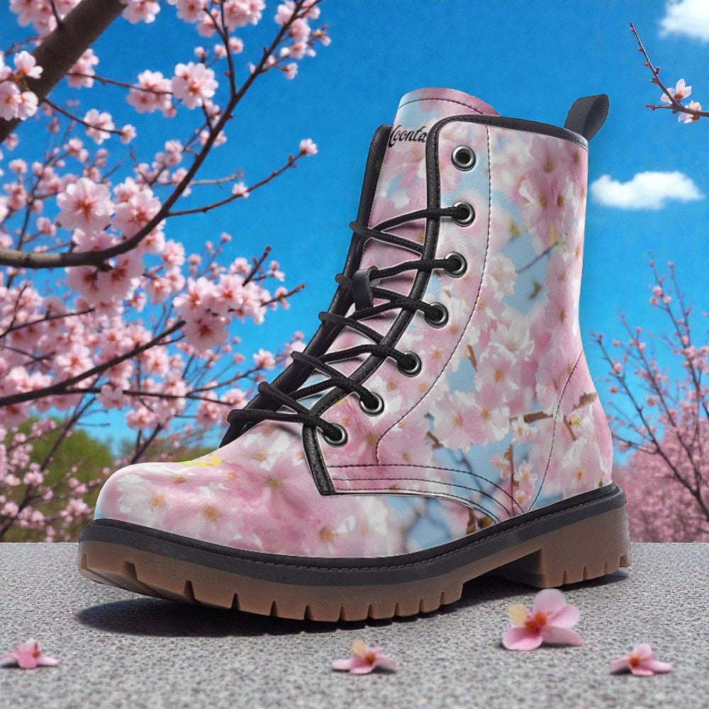 A floral print boot is displayed against a backdrop of blooming cherry blossom trees and a clear blue sky.