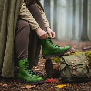 A person is sitting on a log in a forest, wearing green boots and adjusting their shoelaces.