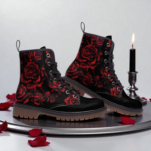 A pair of black boots with red rose patterns, placed on a silver tray with rose petals scattered around.