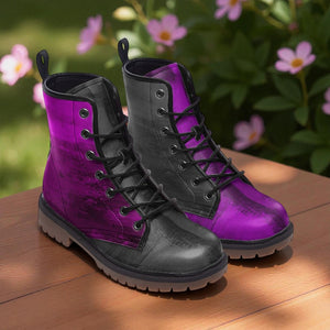 A pair of purple and black boots with laces and soles, placed on a wooden surface with pink flowers in the background.