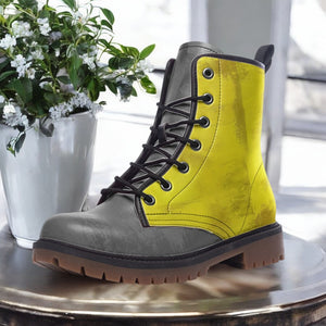 A yellow and gray boot is displayed on a table next to a potted plant with white flowers.
